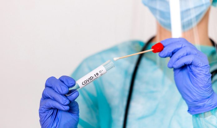 Lab technician holding swab collection kit,Coronavirus COVID-19 specimen collecting equipment,DNA nasal and oral swabbing for PCR polymerase chain reaction laboratory testing procedure and shipping